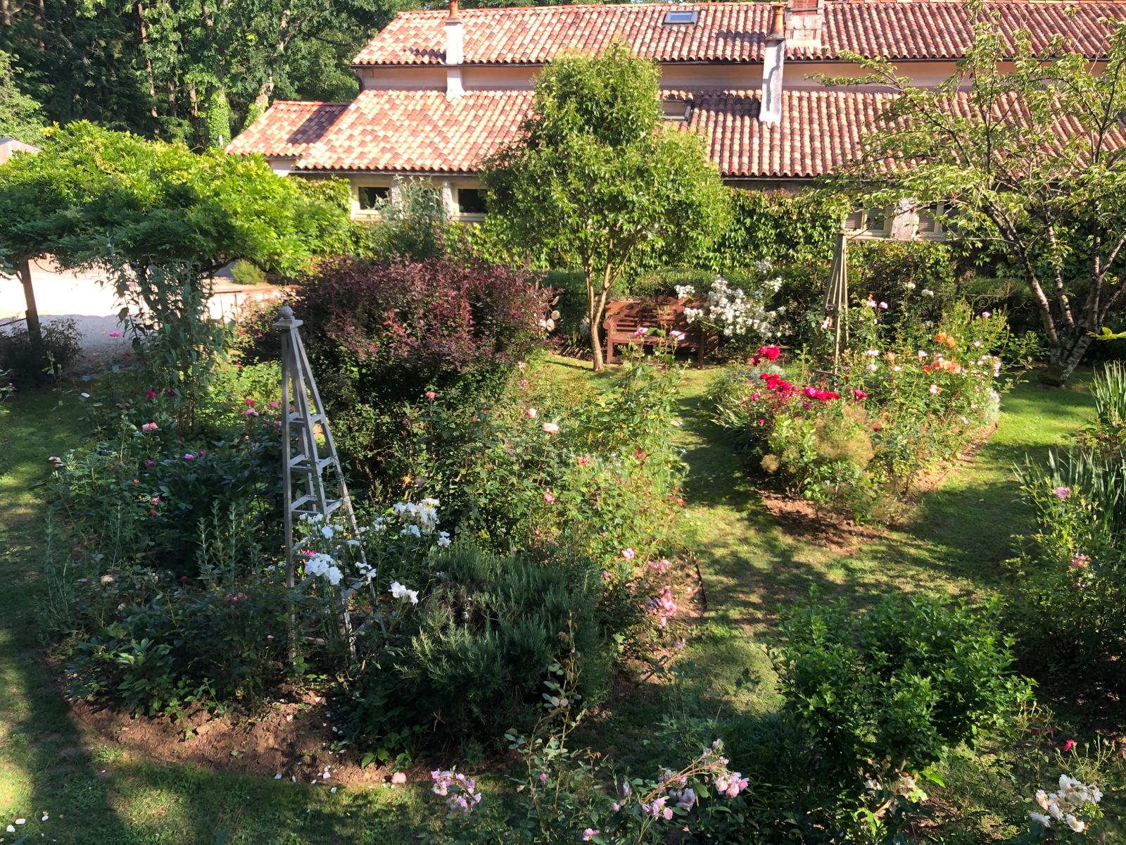 Vue d'ensemble des jardins de Puychereau avec la maison, les massifs de fleurs et les bancs